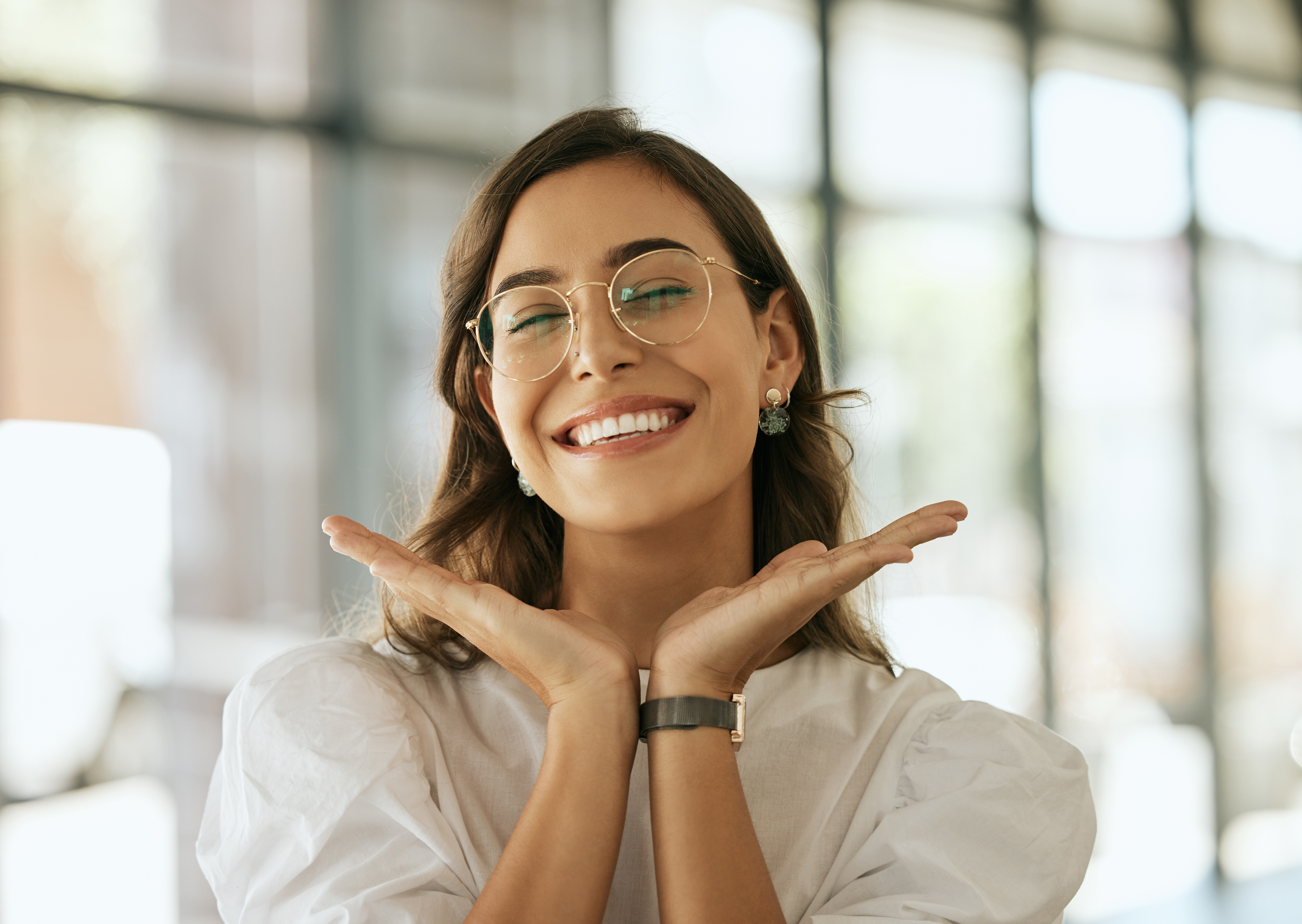 woman smiles with hands by face