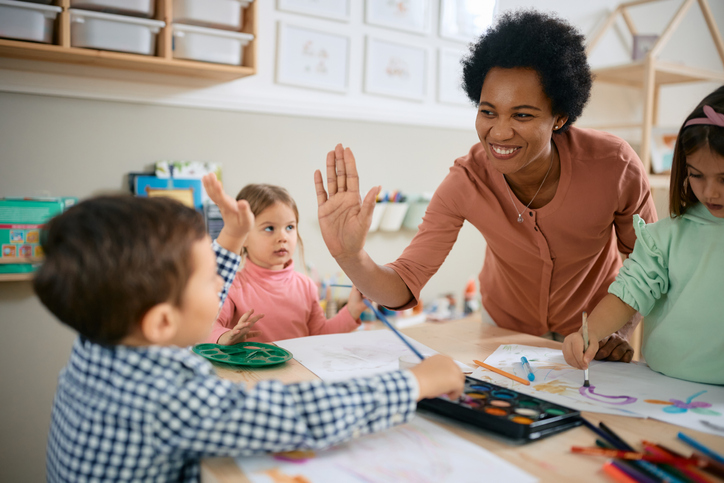 woman high fives preschool student